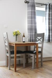 a dining room table with two chairs and a bottle of wine at Avocet Cottage in Lucker