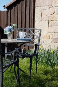 een tafel en stoel met een vaas met bloemen erop bij Avocet Cottage in Lucker