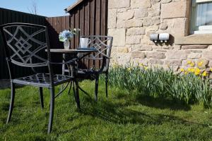 a black chair sitting in the grass with a table at Avocet Cottage in Lucker