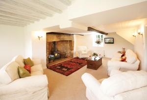a living room with white furniture and a fireplace at Rose Cottage Dorset in Powerstock
