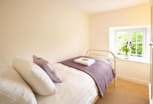 a bedroom with a bed with a blanket and a window at Rose Cottage Dorset in Powerstock