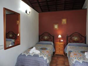 1 dormitorio con 2 camas y espejo en Casas Rurales Casitas Armary, en San Isidro, Breña Alta, en Breña Alta