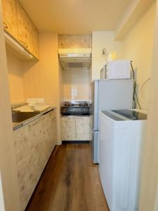 a small kitchen with a white refrigerator and wooden floors at 9-2　NEW！札幌駅7分 好立地【Serviced Apartment SAPPOROステーション9-2】Wi-Fi無料 in Kita-rokujō