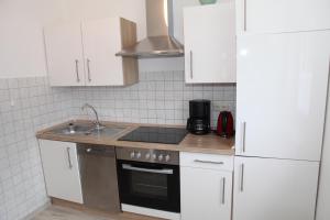 a kitchen with white cabinets and a sink and a refrigerator at Jan Dollart 1 in Greetsiel