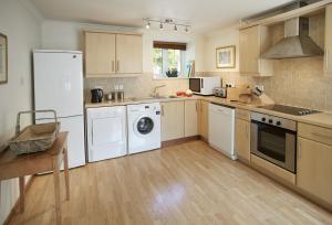 une grande cuisine avec des appareils blancs et du parquet dans l'établissement Mews Cottage, à Helston 8 autres photos