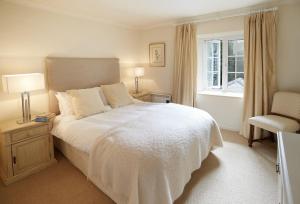 - une chambre avec un lit blanc, une chaise et une fenêtre dans l'établissement Mews Cottage, à Helston