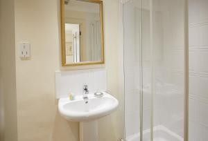 une salle de bain blanche avec un lavabo et une douche dans l'établissement Mews Cottage, à Helston
