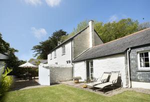 un cottage blanc avec deux chaises dans la cour dans l'établissement Mews Cottage, à Helston