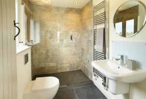 a bathroom with a sink and a toilet and a mirror at Furlong Barn in Southam