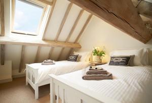 two beds in a attic room with a window at Furlong Barn in Southam