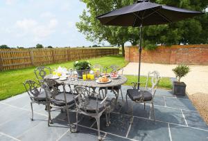 a table and chairs with an umbrella on a patio at Furlong Barn in Southam