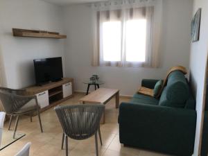 salon z zieloną kanapą i telewizorem w obiekcie Rocasol - Suites w mieście Calpe