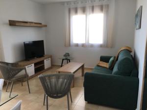 sala de estar con sofá verde y TV en Rocasol - Suites, en Calpe