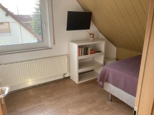 1 dormitorio con 1 cama, TV y ventana en Gästezimmer zum Waldsachsener Grund en Meerane