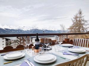 a table with plates and wine glasses on a balcony at Apartment Ambassador I Apt 7 by Interhome in Nendaz