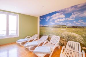 ein Zimmer mit Stühlen und einem Wandbild eines Feldes in der Unterkunft Hotel Tanne Ilmenau in Ilmenau