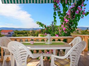 ein weißer Tisch und Stühle auf einem Balkon mit Blumen in der Unterkunft Apartment Andjelka by Interhome in Malinska