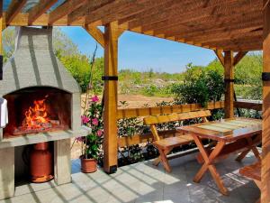 einen Kamin auf einer Terrasse mit einer Bank und einem Tisch in der Unterkunft Apartment Andjelka by Interhome in Malinska