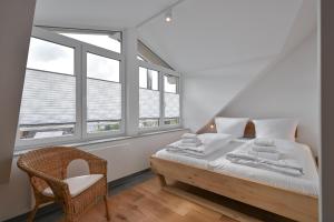 a bedroom with a bed and a chair and windows at Ferienwohnung Carpe Diem in Füssen