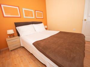 a bedroom with a large bed with white sheets and a night stand at Apartment Bencun-2 by Interhome in Makarska