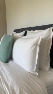 Maison Divon في مونتانيو: سرير ابيض مع مخدات بيضاء ومخدة خضراء