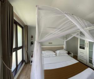 een slaapkamer met een wit bed en een baldakijn bij Zebi Ecolodge in Hoima