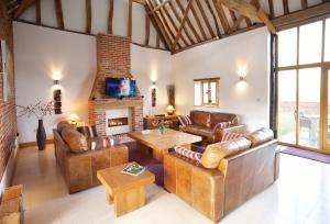 a living room with leather furniture and a fireplace at Thatch Barn in Lingwood
