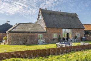 a large brick house with a fence in front of it at Thatch Barn in Lingwood