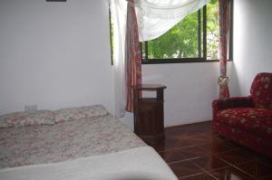 ein Schlafzimmer mit einem Bett, einem Stuhl und einem Fenster in der Unterkunft Papaya Guesthouse in Mahé