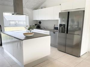 a kitchen with white cabinets and a stainless steel refrigerator at Holiday Home Dwerg - 1-5km from the sea in NW Jutland by Interhome in Løkken