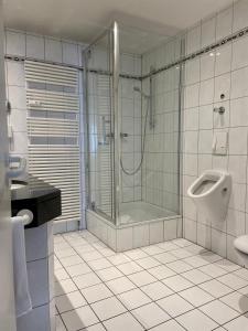 ein Bad mit einer Dusche, einem Waschbecken und einem Urinal in der Unterkunft Hotel Wittlicher Hof in Wittlich