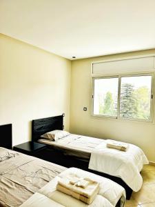 een slaapkamer met 2 bedden en een raam bij Magnifique appartement en plein centre ville in Kenitra
