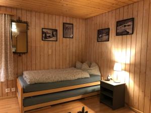 - une chambre avec un lit dans un mur en bois dans l'établissement Apartment Lohnerblick by Interhome, à Adelboden