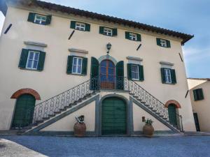 - un grand bâtiment blanc avec des portes et des escaliers verts dans l'établissement Holiday Home Villa La Guardia Vecchia-1 by Interhome, à Crespina