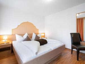 a bedroom with a white bed and a black chair at Apartment Rosa-10 by Interhome in Mayrhofen +20 photos