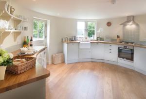 a kitchen with white cabinets and a wooden floor at Bakers Farm Oast in Ticehurst +8 photos