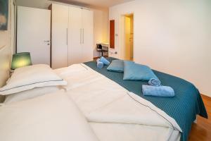 a large white bed with blue pillows on it at Apartment Jelka 1 in Krk