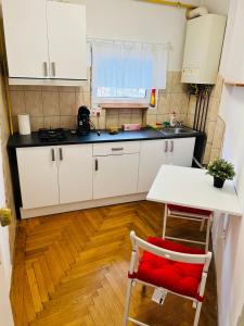 cocina con armarios blancos, mesa y silla roja en Unirii Downtown Apartment, en Bucarest