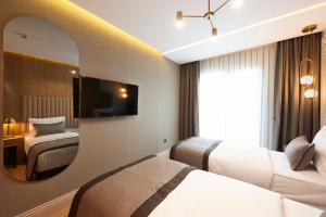 イスタンブールにあるDundar Hotel & Spaのベッド2台と鏡が備わるホテルルームです。
