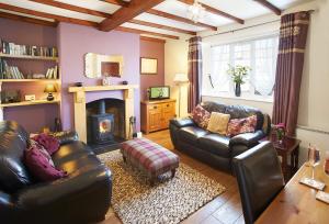 a living room with two leather couches and a fireplace at Heather Cottage in Gillamoor