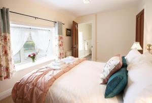 a bedroom with a large white bed with a window at Heather Cottage in Gillamoor