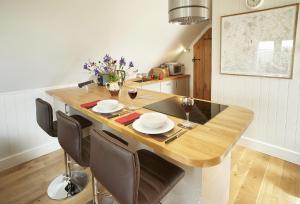 a kitchen with a wooden table with chairs and wine glasses at The Loft in South Stoke