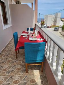 a table and chairs on a balcony with a red table cloth at Roumeliotis house in Karpathos