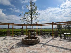 eine Terrasse mit einem Baum, Tischen und Stühlen in der Unterkunft Gasthaus Beinker in Ostercappeln