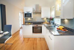 uma cozinha com armários brancos e uma tigela de fruta no balcão em The Cwtch em Pencoed