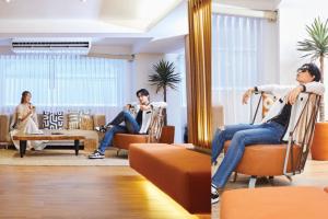 2 personas sentadas en sillas en una sala de estar en Arck Hotel en Bangkok