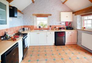 a kitchen with white cabinets and a black dishwasher at Rhiwelli in Dinas
