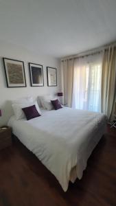 ein großes weißes Bett in einem Schlafzimmer mit Fenster in der Unterkunft Mélodie Garage Gratuit in Cannes