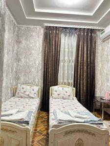 two twin beds in a room with curtains at Yusuf Gold House in Samarkand