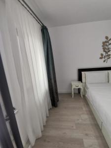 Schlafzimmer mit weißen Vorhängen und einem Bett in der Unterkunft Casa Dorin in Orşova